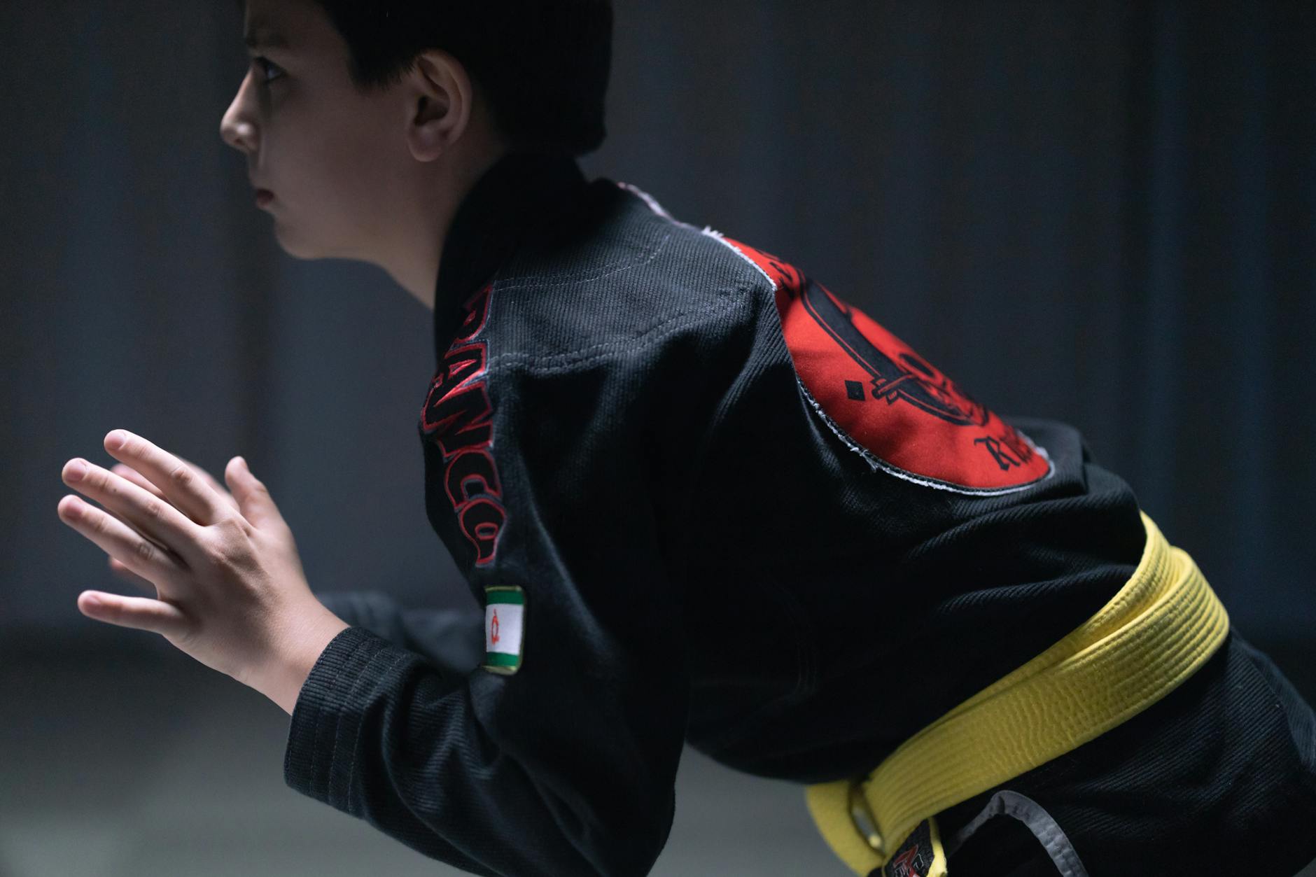 A young boy practicing martial arts in a jiu jitsu gi indoors, showcasing focus and determination.