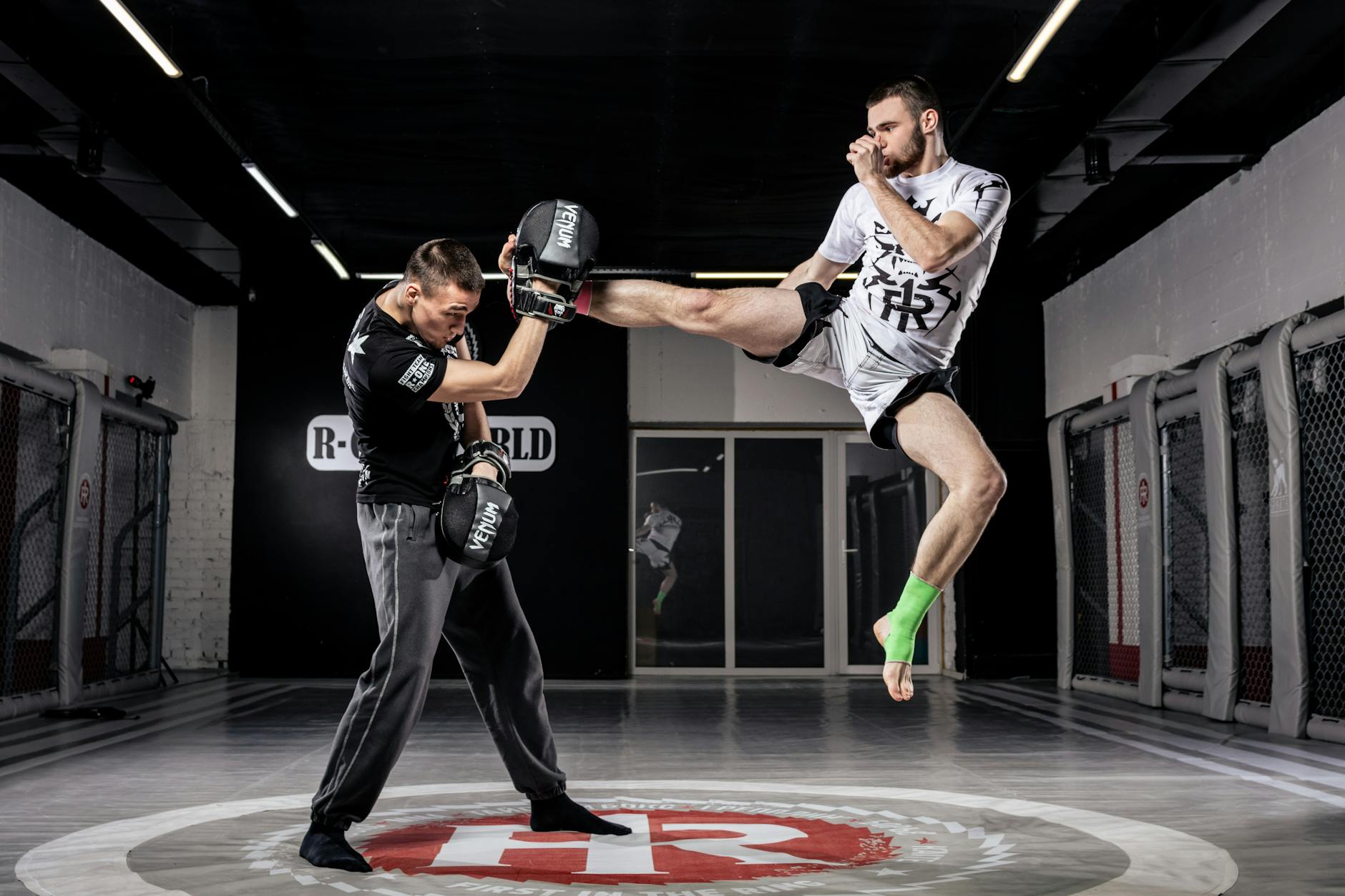 Two men practicing intense martial arts in a modern indoor gym. Action-packed training session.